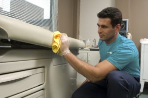 Person cleaning exam table